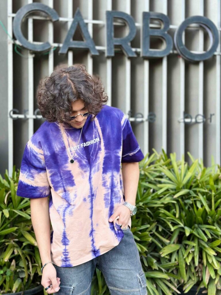 Men in Mix Purple-Cream Acid Wash Oversized T-Shirt with goggles in sytle in front of garden