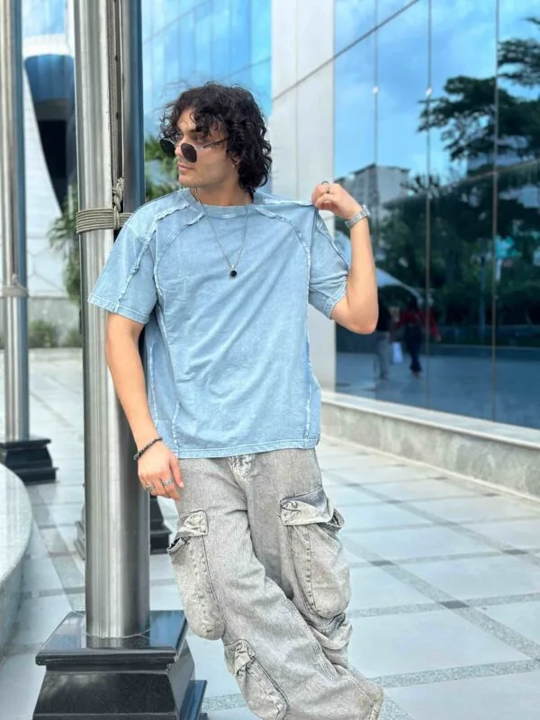 A man wearing the light blue acid wash pintex oversize tshirt showing the dropped shoulders and comfortable fit perfect for a contemporary casual outfit