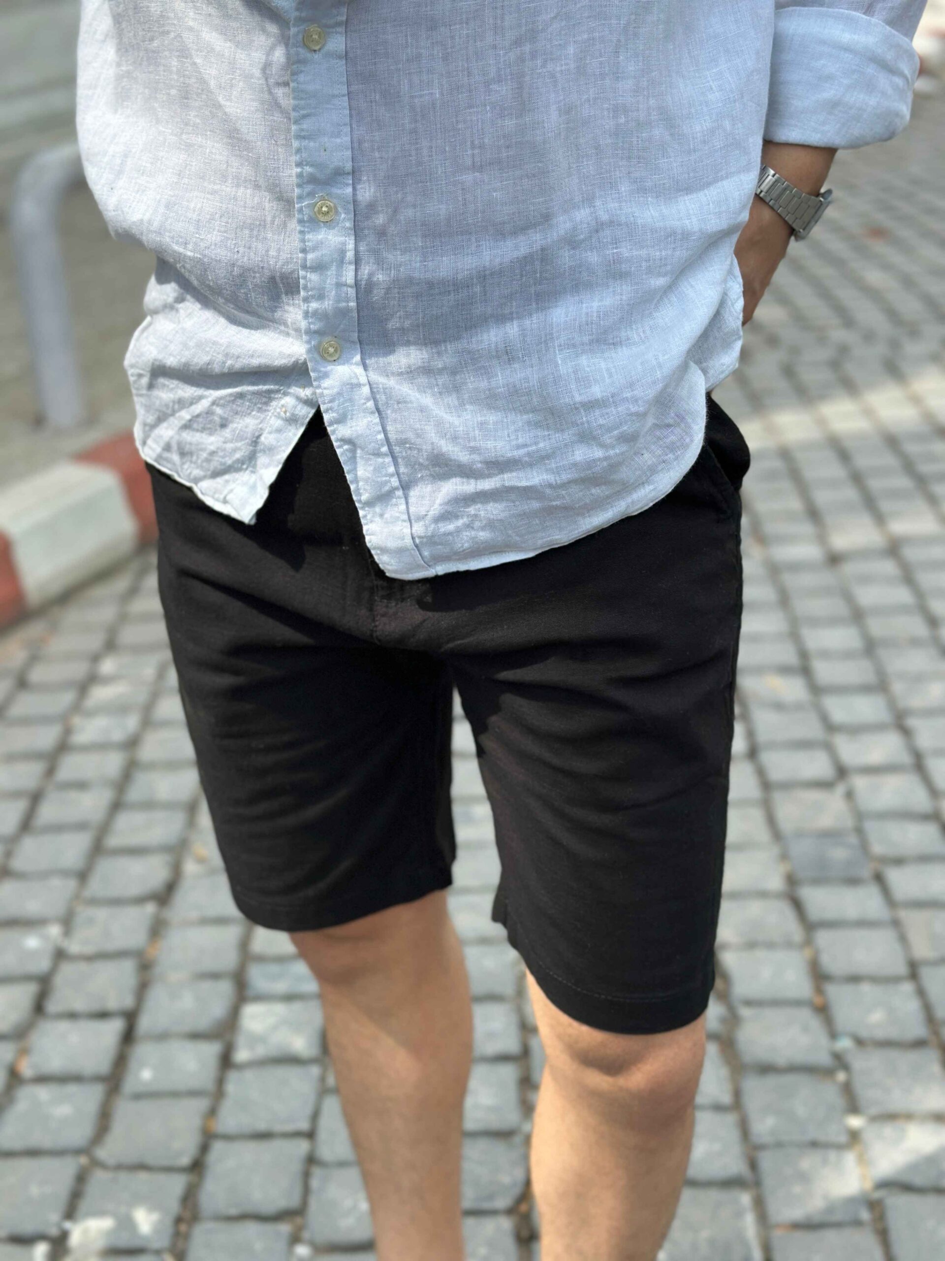 Close-up on the breathable fabric and cut of the men's black linen shorts.