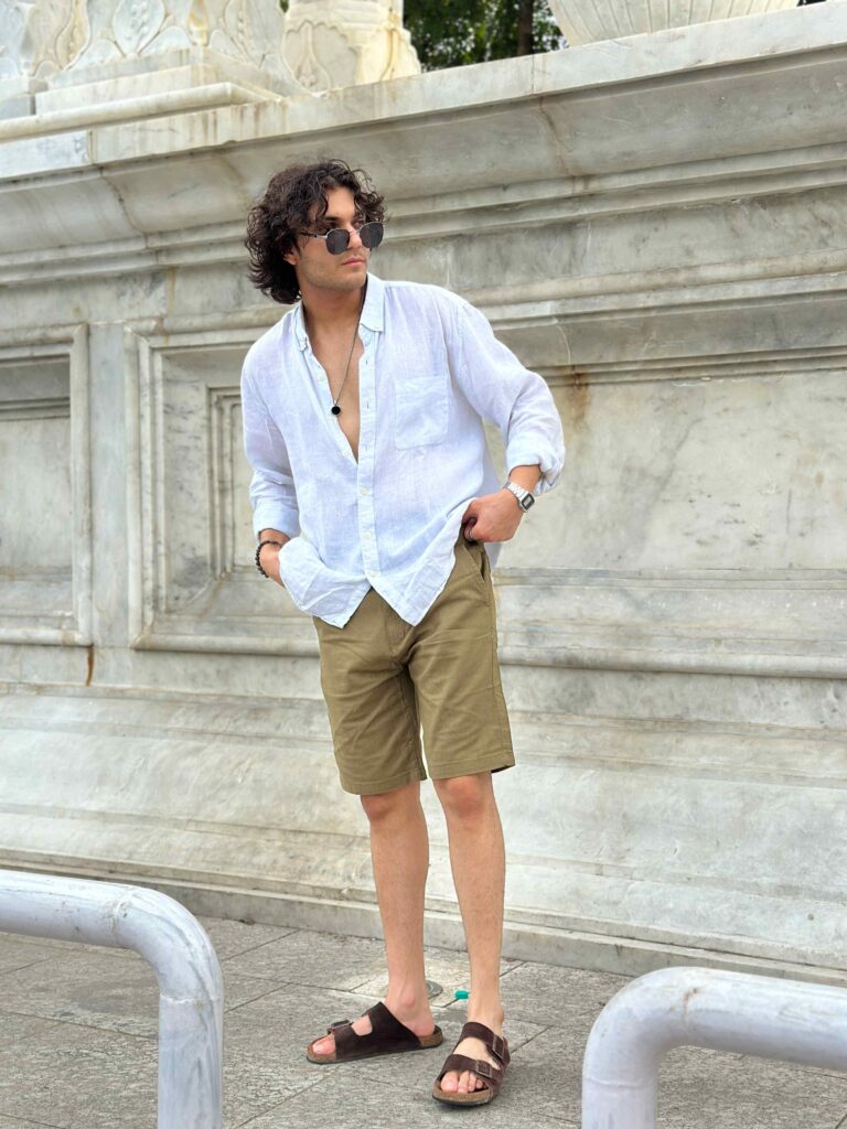 Comfortable men's khaki linen shorts with a relaxed fit, shown with a casual white button-up shirt and sandals.