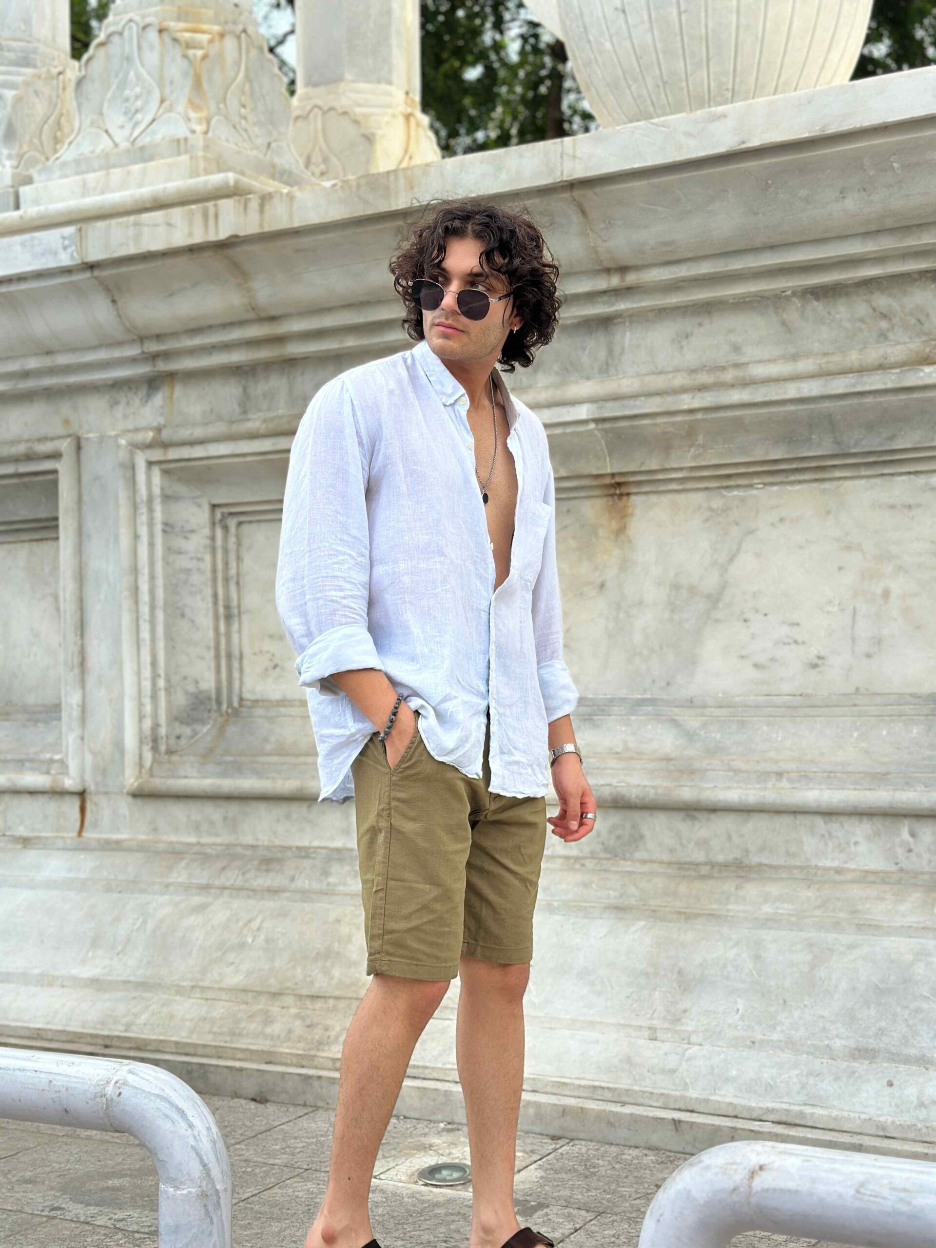 Side view of a man wearing fashionable khaki linen shorts, showcasing the fit and style, paired with a light, open-collared shirt.