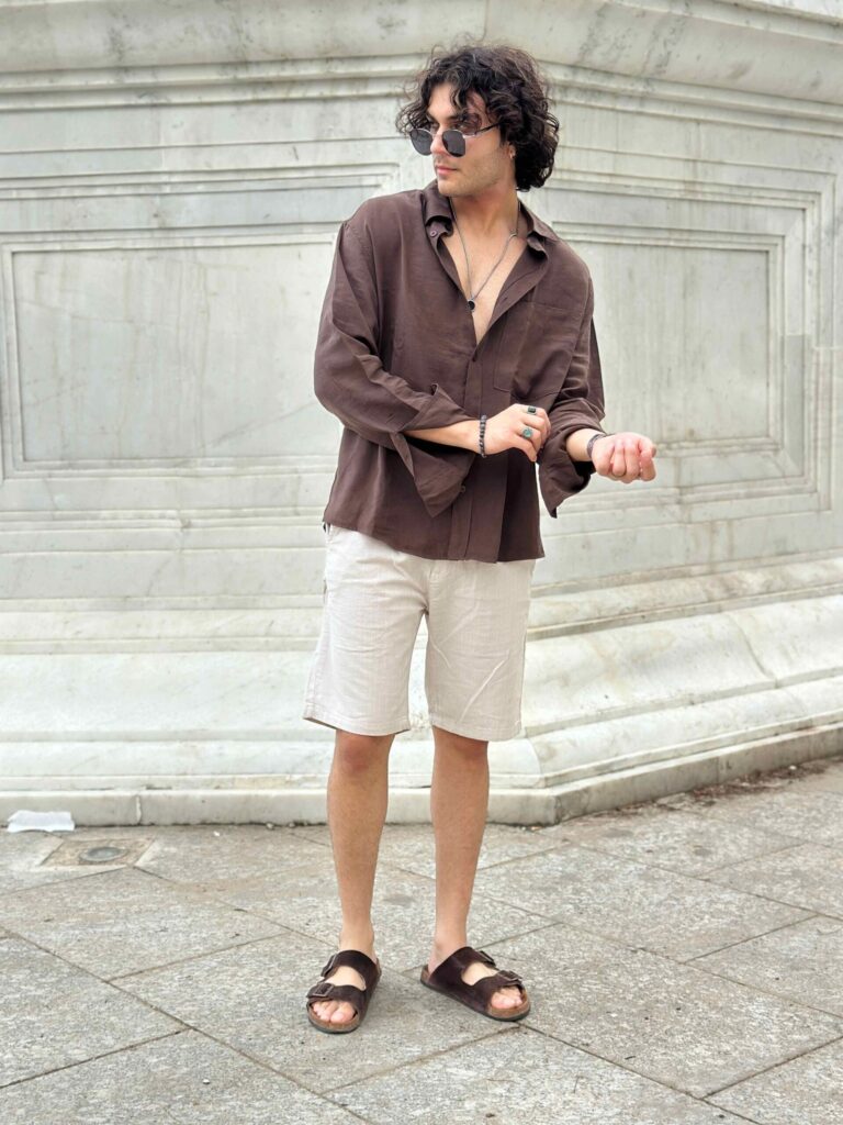 Man-adjusting-his-sleeve-while-wearing-beige-linen-shorts-emphasizing-the-shorts-versatility-and-relaxed-fit-a-great-addition-to-any-mens-summer-wardrobe-scaled